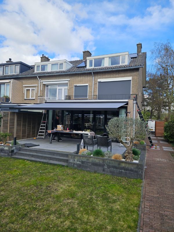 Detailopname van een knikarmscherm aan een Hilversums jaren dertig huis met bakstenen gevel